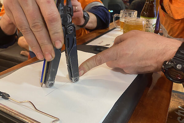 A man using a multi-tool to measure the distance on a piece of paper