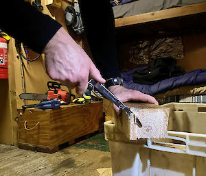 A close up of a man sawing a corner of a piece of wood using a multi-tool