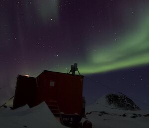 A green aurora in the night sky above the Colbeck field hut.