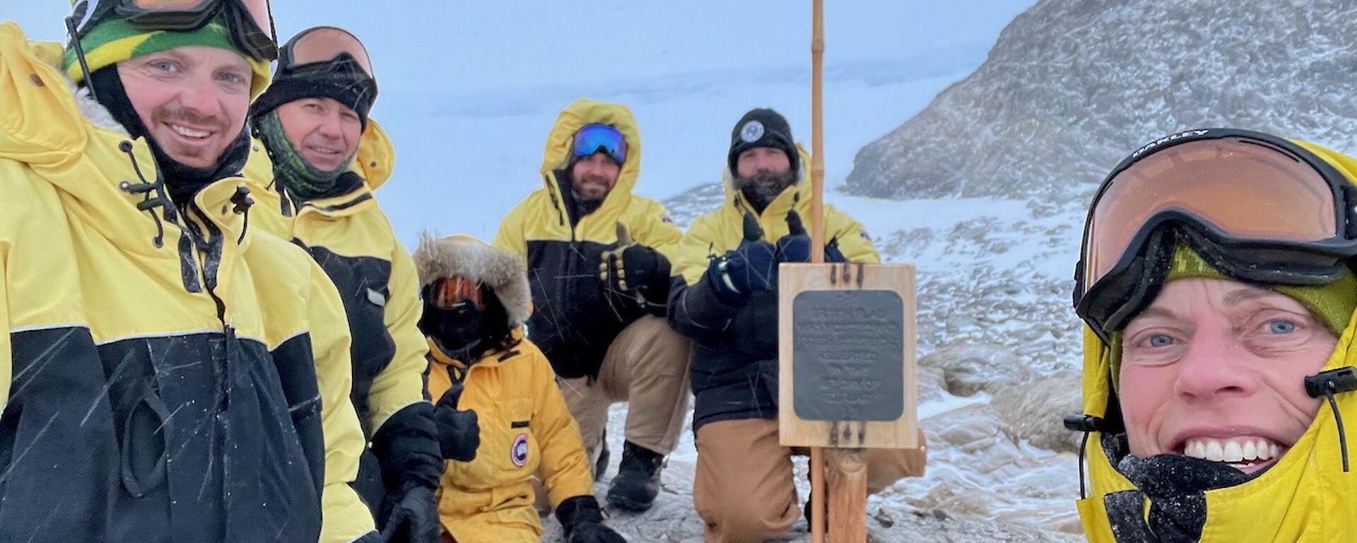 Six expeditioners gathering around the signpost at Proclamation Point.