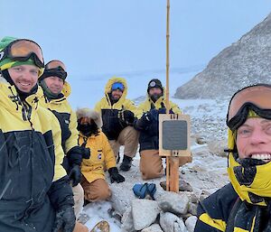 Six expeditioners gathering around the signpost at Proclamation Point.