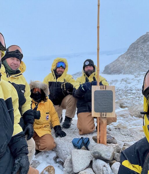 Six expeditioners gathering around the signpost at Proclamation Point.