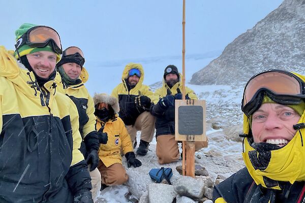 Six expeditioners gathering around the signpost at Proclamation Point.