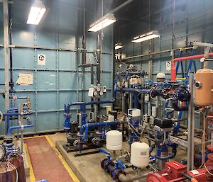 Inside a large warehouse shed filled with a series of pipes and tanks and other plumbing equipment