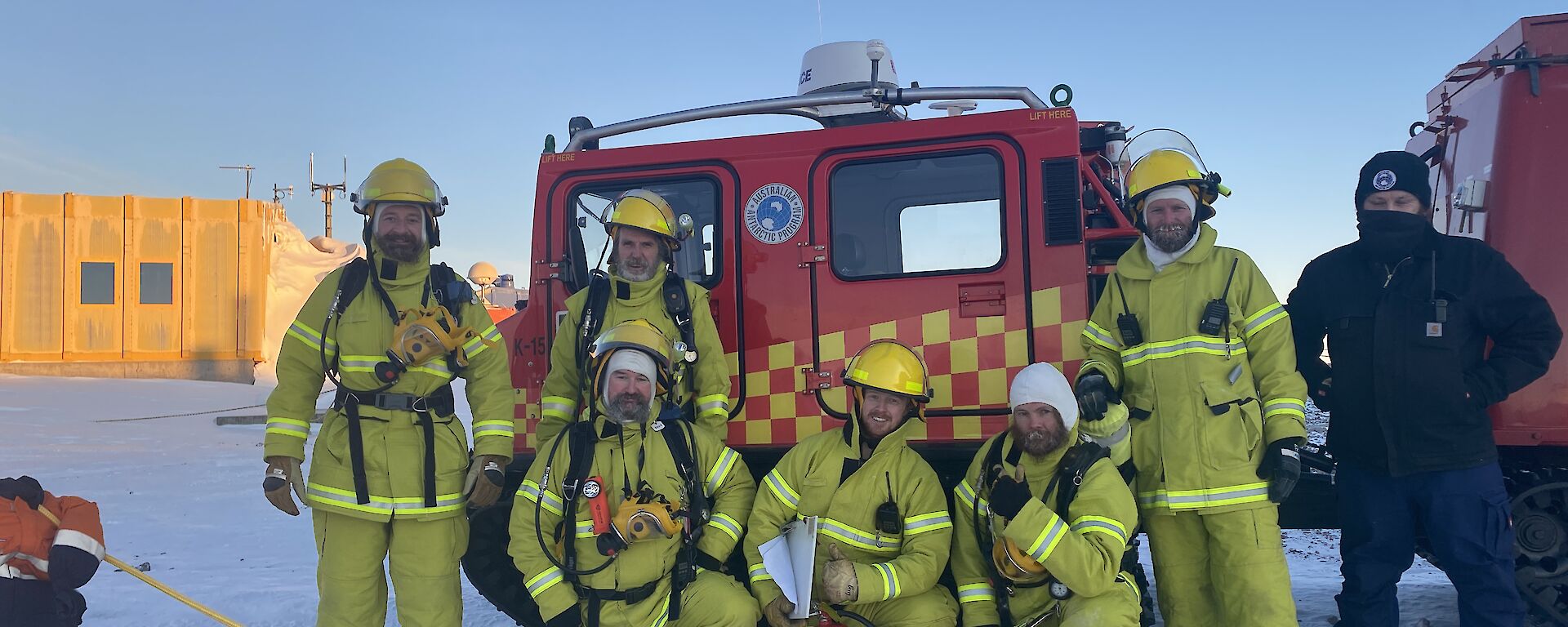 A group photo of people in fire safety gear and helmets in front of a red emergency Hagglund