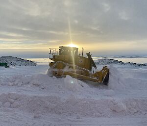 A bulldozer navigating the peaks of a large snow blizz to try and clear the snow