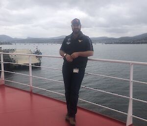 Expeditioner leaning against the ship's handrail with Hobart in the background.