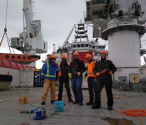 Five expeditioners in safety clothing working on the rear deck of the MPV Everest.