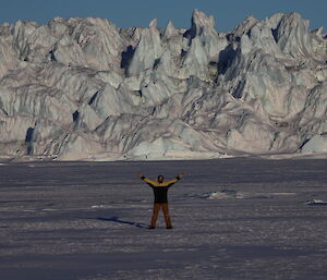 A man raises his arms with the Sørsdal Glacier behind him