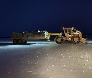 A tractor on the ice with a trailer loaded with pallets from the airdrop