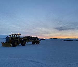 A tractor on the ice with a trailer loaded with pallets from the airdrop