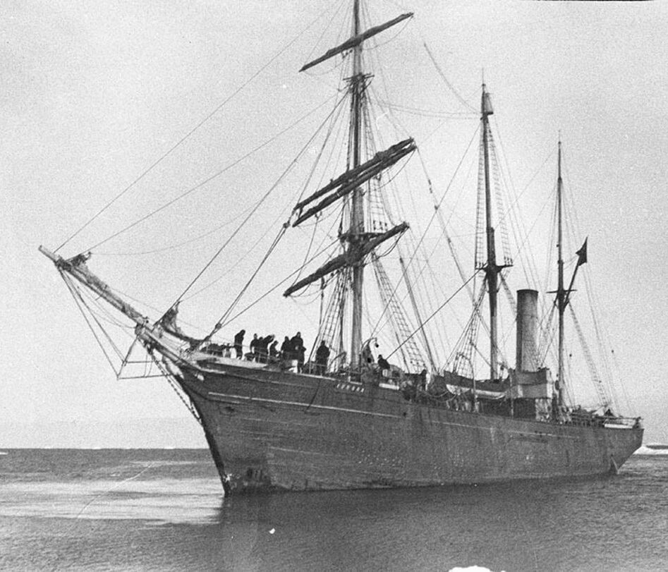 Black and white photo of a wooden ship in Antarctica in the early 1900s.