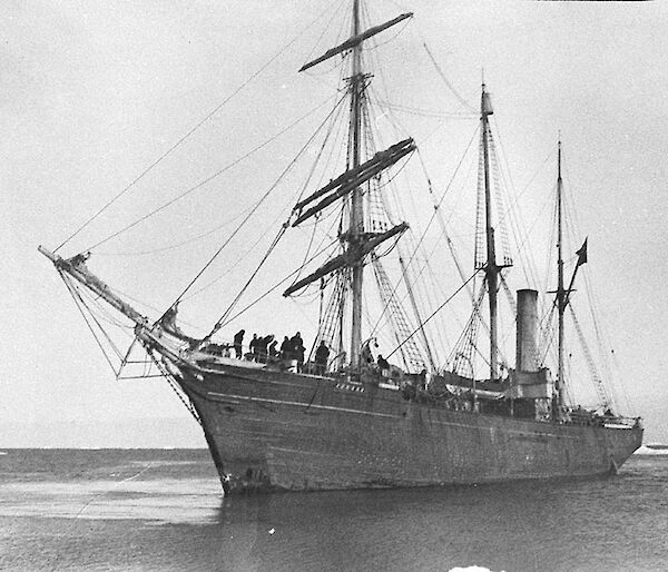 Black and white photo of a wooden ship in Antarctica in the early 1900s.