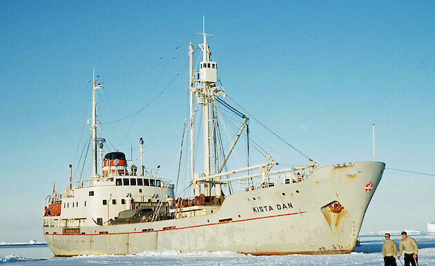 Icebreaker Kista Dan in ice, with two men skiing past the bow.