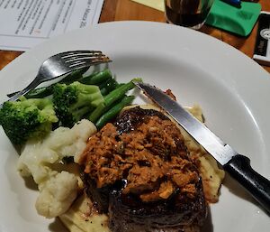 A plate of steak and polenta with a side of greens.