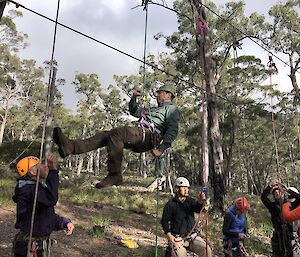 A man elevated off the ground as he climbs a rope.