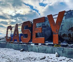 A large orange sign spelling CASEY with peeling paint and dents