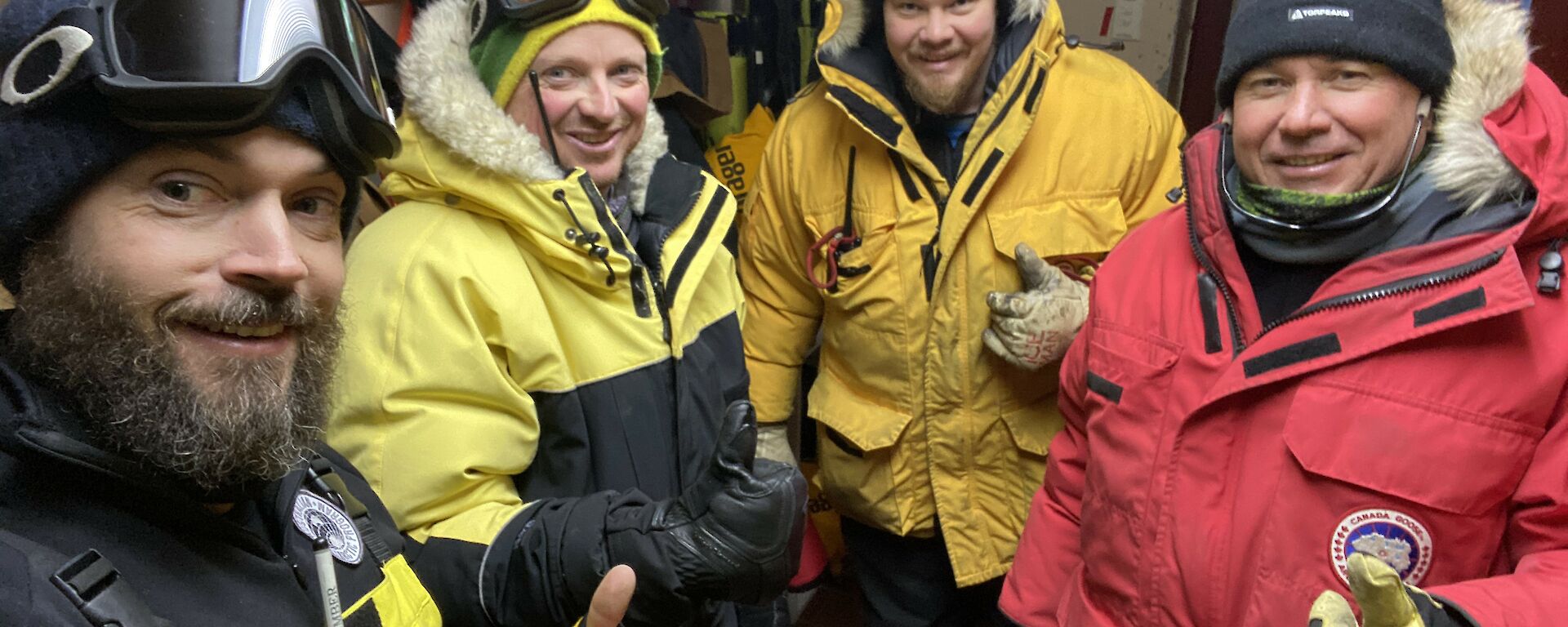 Four expeditioners in their winter clothing about to leave the cold porch.