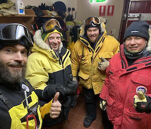 Four expeditioners in their winter clothing about to leave the cold porch.