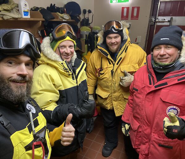 Four expeditioners in their winter clothing about to leave the cold porch.
