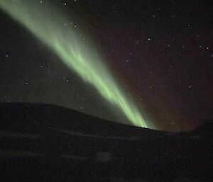 An green aurora in the night sky taken on a mobile phone.
