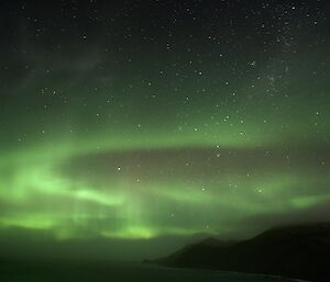 The night sky lit with waves of green aurora