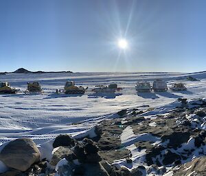 A panoramic shot across an icy Antarctic landscape with a convoy of vehicles traversing across the snow