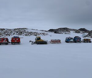 A small convoy of Hagglunds with a snow plow and sled on the sea ice