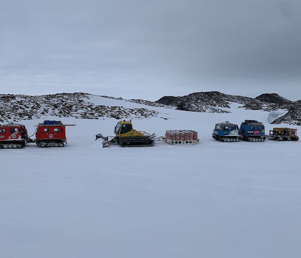 A small convoy of Hagglunds with a snow plow and sled on the sea ice