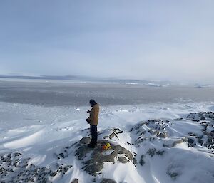 Man standing on ridge of a rocky outcrop amongst the snow