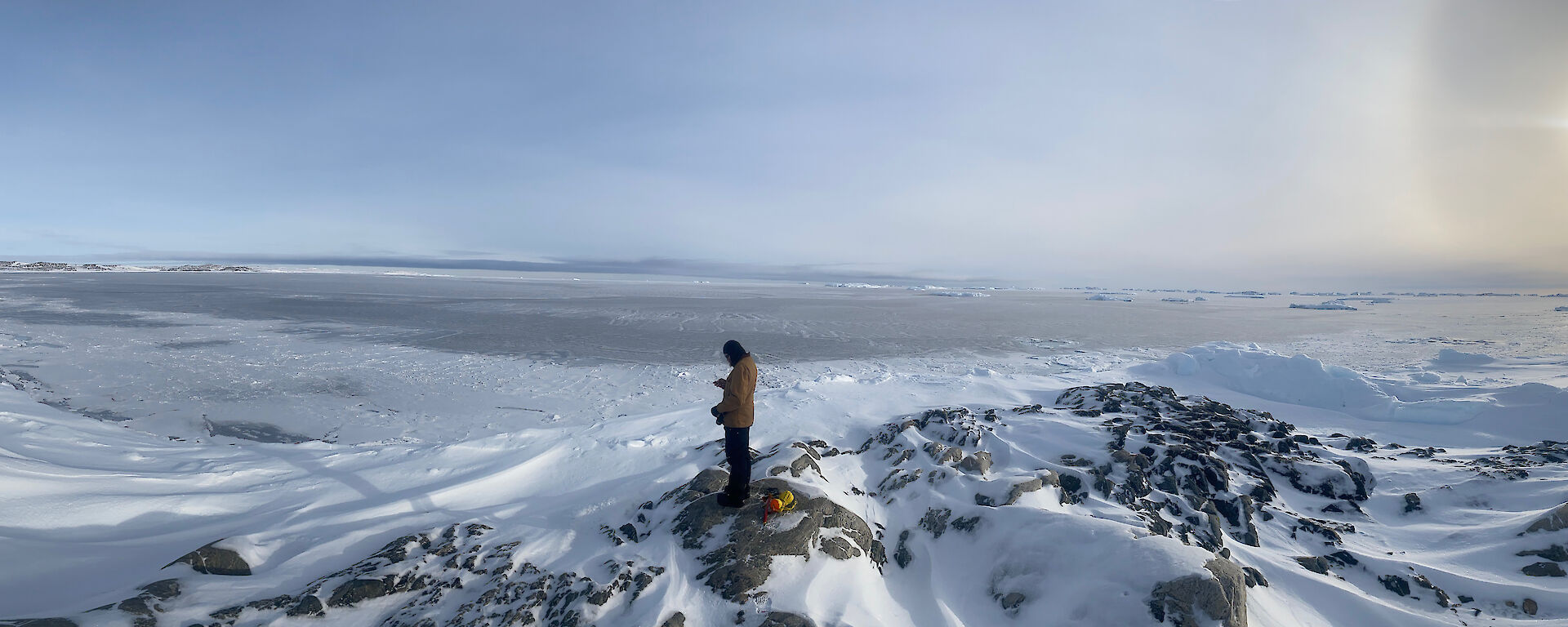 Man standing on ridge of a rocky outcrop amongst the snow