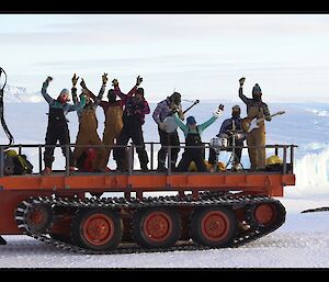 Eight expeditioners on the back of the pioneer trailer dancing