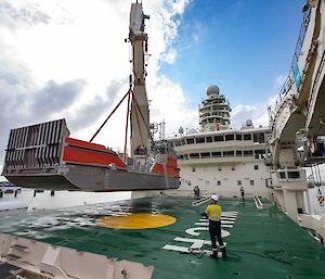 A barge being craned onto the bow of the ship with one of its 50 tonne cranes.