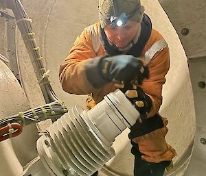 A man in cold weather clothing inside the nose cone at the top of the wind turbine.