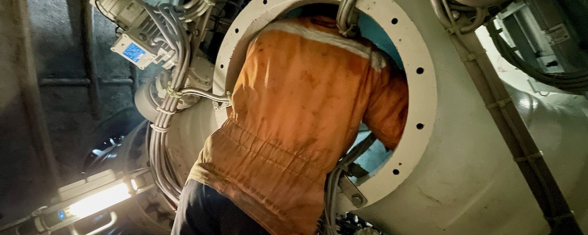 A man leaning inside an entry hatch of the wind turbine.