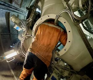 A man leaning inside an entry hatch of the wind turbine.