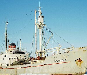 A picture of a grey ship amongst the sea ice with blue skies