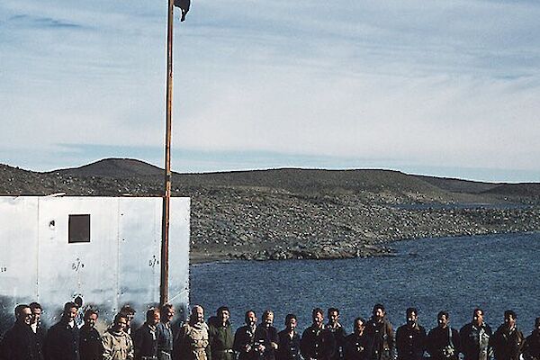 A group shot of the official flag raising for the opening of Davis station with a rocky outcrop in the background