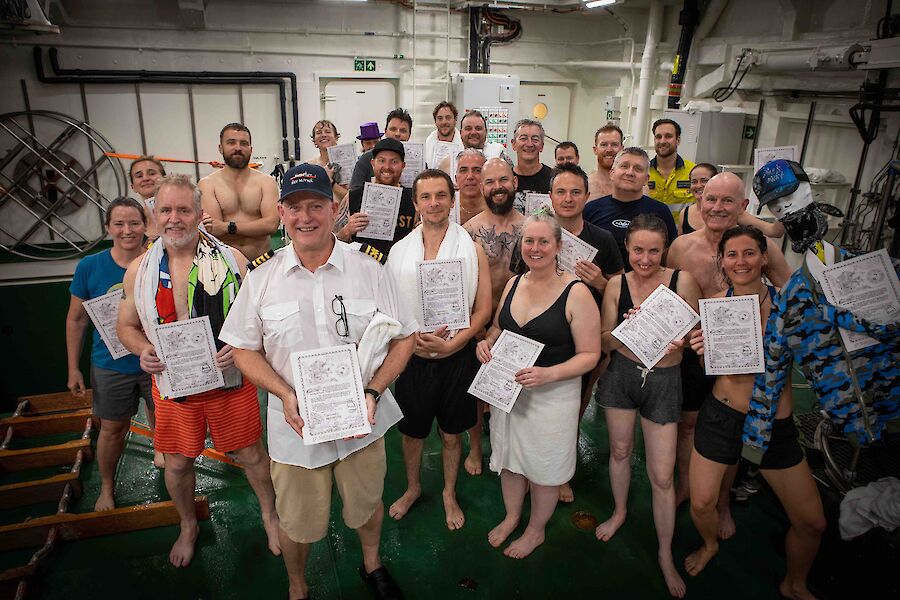 A group of people in bathers holding up certificates and smiling to camera