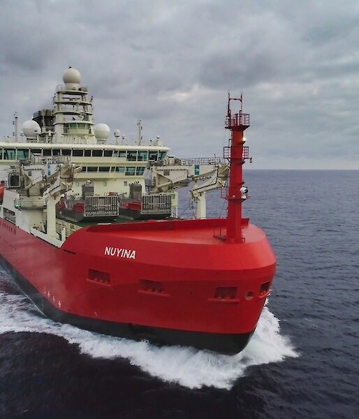 A ship sales through the sea under grey skies