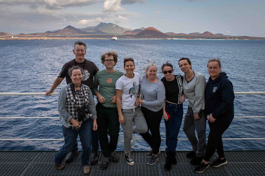 A group shot standing by the ship handrail with Ascension Island in the background