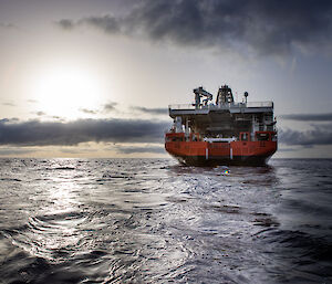 The stern of a large red ship on a moody ocean