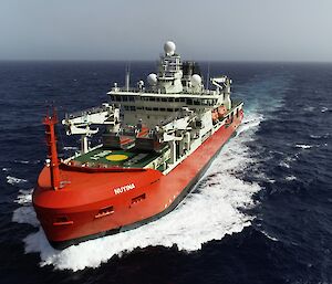 Large red ship sailing through the ocean on a sunny day