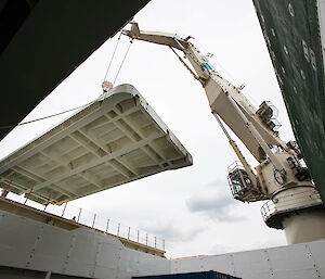 Ship based crane lifts a pontoon deck into place