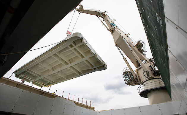 Ship based crane lifts a pontoon deck into place