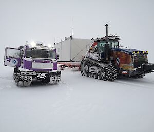 Two large machines covered in snow are used to transport people and equipment