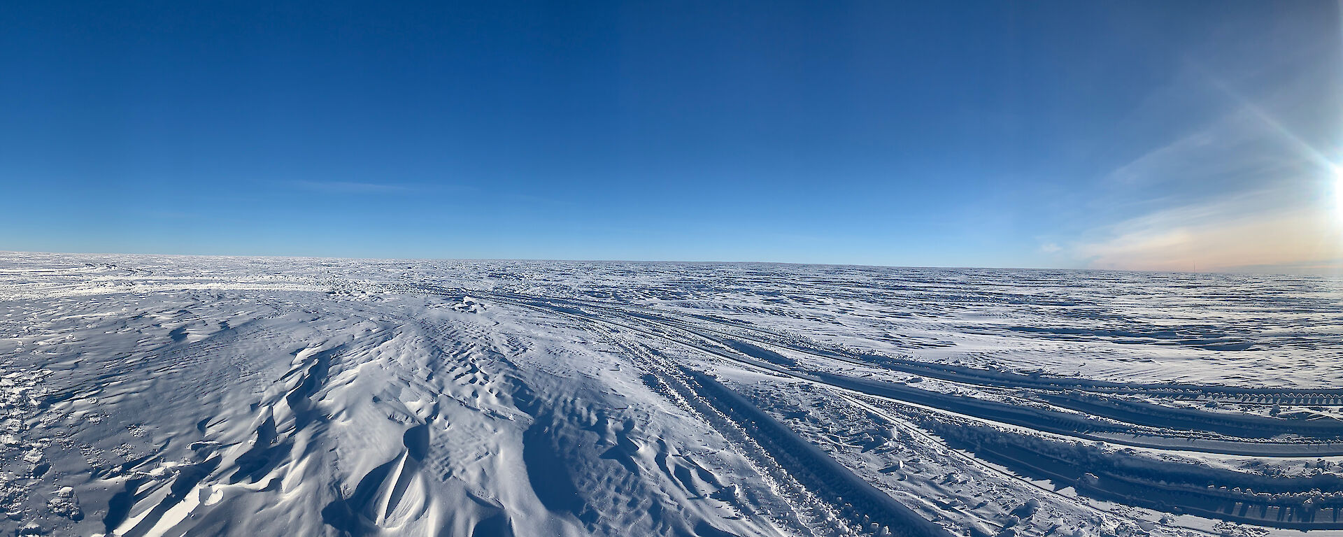 Panoramic shot of snow with the sun low on the horizon