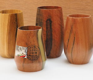 Four wooden cups with varying patterns sit on a white bench