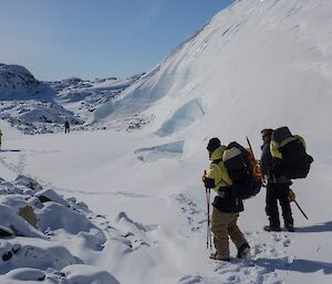 A group of people walking through the snow in a small valley