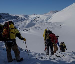 A group of people negotiating a snowy downhill section of a hill